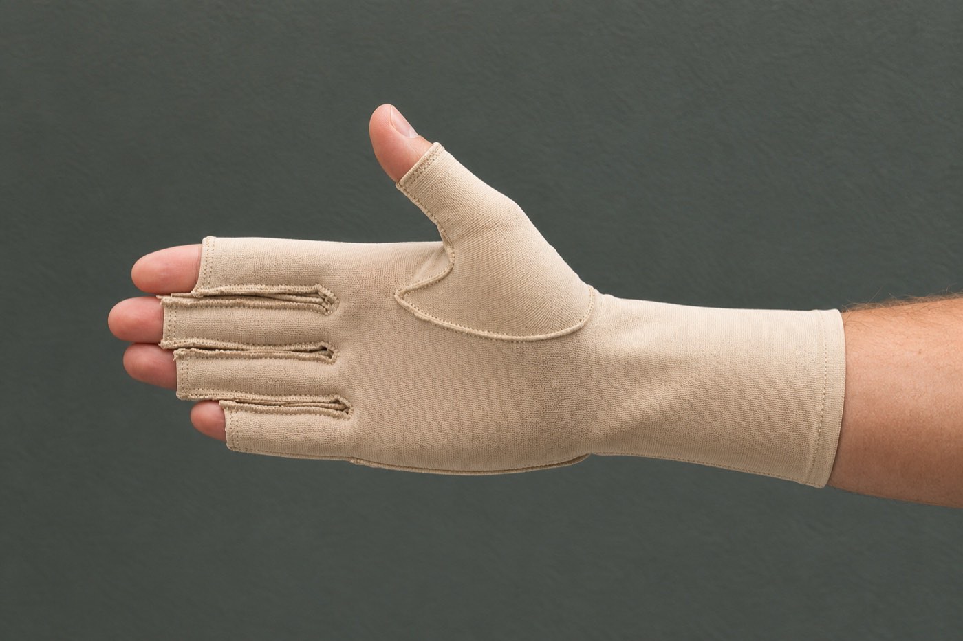 A hand wearing a beige fingerless compression glove for oedema management