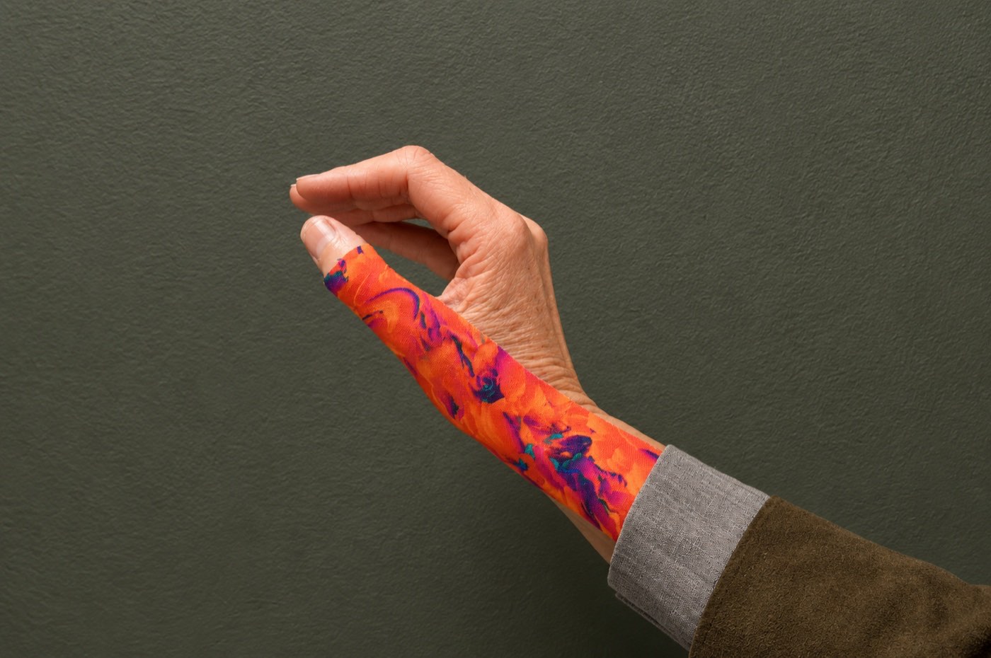 A thumb and hand wrapped in colourful patterned taping